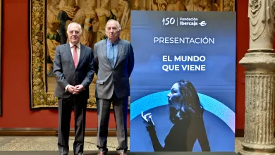 Two men in suits stand on a stage beside a blue banner reading 'PRESENTACIÓN EL MUNDO QUE VIENE'.