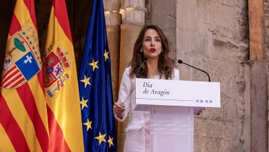 Female speaker at a podium with Spanish and European Union flags, delivering a speech.