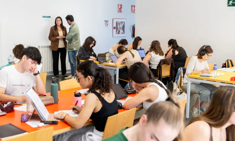 Group of Students Seated at Orange Tables Working on Laptops and Papers While Two Adults Stand Near the Wall in the Background Las Bibliotecas Del Actur Y Las Fuentes Abrirán Hasta Madrugada Durante Los Exámenes Zaragozala Qué Hacer En Zaragoza