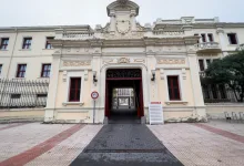 Ornate historic building entrance with decorative carvings and a central archway, road leading through to a courtyard.