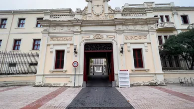 Ornate historic building entrance with decorative carvings and a central archway, road leading through to a courtyard.