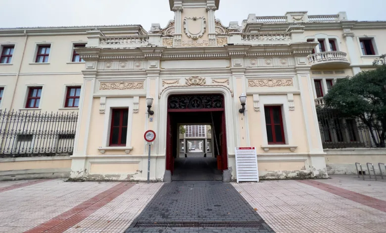 Ornate historic building entrance with decorative carvings and a central archway, road leading through to a courtyard.