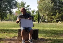 Man in a Patterned Shirt and Shorts Sits on a Tree Stump in a Park Holding an Open Sketchbook with Drawings for Others to See Zaragoza Qué Hacer En Zaragoza Zaragozala Qué Hacer En Zaragoza