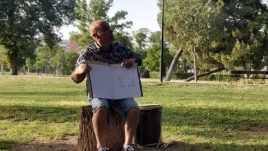 Man in a Patterned Shirt and Shorts Sits on a Tree Stump in a Park Holding an Open Sketchbook with Drawings for Others to See Zaragoza   Qué Hacer En Zaragoza Zaragozala   Qué Hacer En Zaragoza