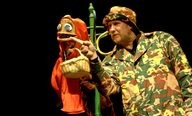 Man in Camouflage Jacket and Hat Points Toward a Wicker Basket Puppet Wearing a Red Hood on a Dark Stage Background Zaragoza Qué Hacer En Zaragoza Zaragozala Qué Hacer En Zaragoza