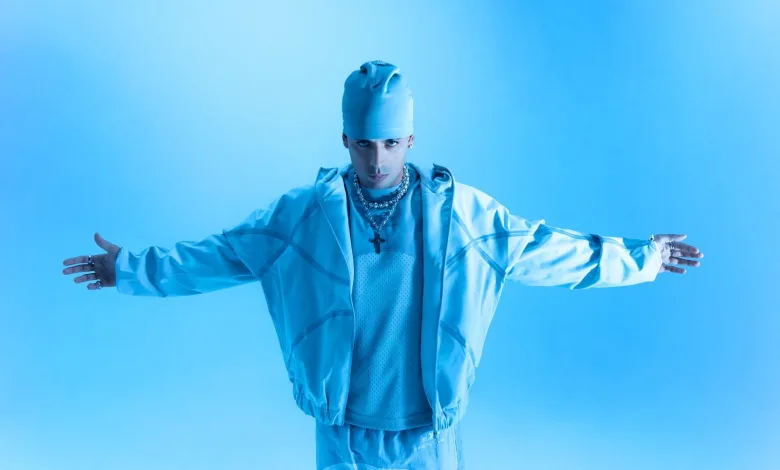 Person in All blue Outfit tank Top Jacket Beanie with Arms Outstretched Against a Blue Background Bold Fashion Pose Inverfest Zaragoza 2027 Anuncia Sus Primeros Conciertos Zaragozala Qué Hacer En Zaragoza