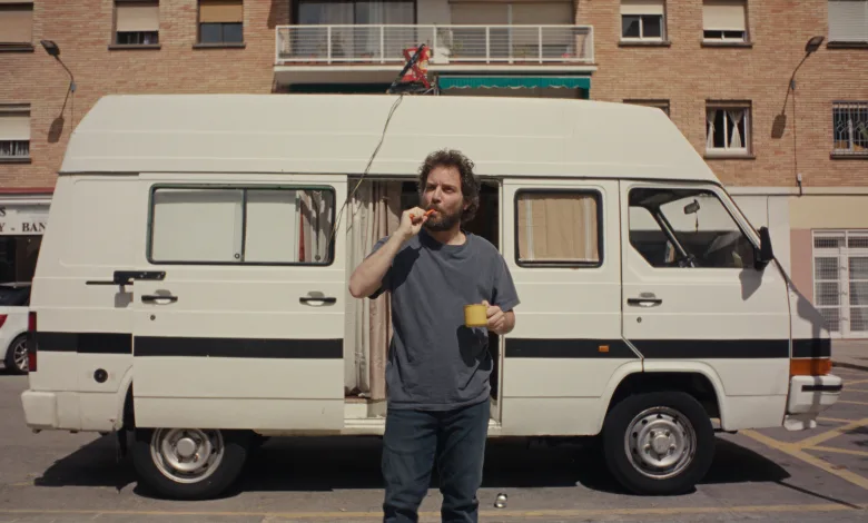 Man in a Gray T shirt Stands Beside a White Camper Van in a Parking Lot Eating an Orange Snack and Holding a Yellow Mug Zaragoza Qué Hacer En Zaragoza Zaragozala Qué Hacer En Zaragoza