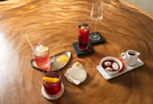 Assorted Desserts and Drinks on a Polished Wooden Table Red Cocktails a Sparkling Crushed ice Drink and a White Creamer Alongside a Small Dessert Tray with Mochi Balls Zaragoza Qué Hacer En Zaragoza Zaragozala Qué Hacer En Zaragoza