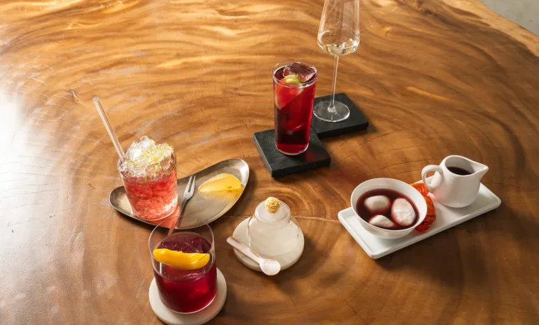 Assorted Desserts and Drinks on a Polished Wooden Table Red Cocktails a Sparkling Crushed ice Drink and a White Creamer Alongside a Small Dessert Tray with Mochi Balls Cariñena Spritz Este Fin De Semana En Plaza De Los Sitios Zaragozala Qué Hacer En Zaragoza