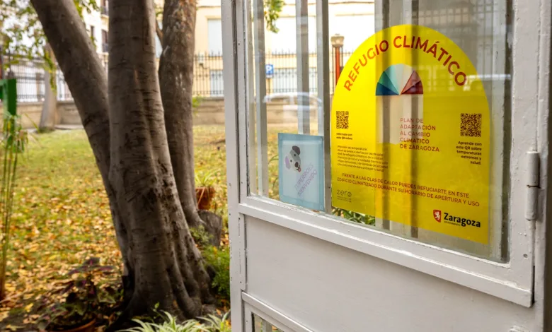 Yellow Climate Refuge Poster on a Glass Door with Text refugio ClimÁtico and a Color Wheel Located in a Small Booth by Trees Outside Zaragoza Activa Su Red De Refugios Climáticos Con Más De 60 Espacios Municipales Frente Al Calor Zaragozala   Qué Hacer En Zaragoza