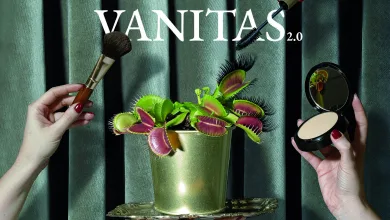 Promotional image for Vanitas 2.0 by Olga S. Ortiz: hands hold makeup brushes around a green Venus flytrap in a gold pot against velvet backdrop.