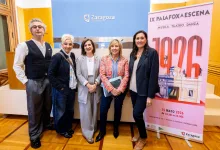 Five people posing together at an event in a room with a Zaragoza sign and a pink poster in the background.