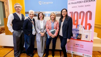 Five people posing together at an event in a room with a Zaragoza sign and a pink poster in the background.