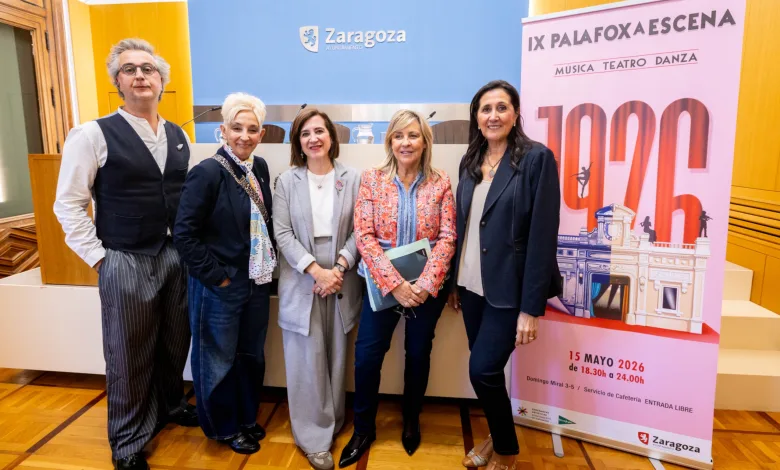 Five people posing together at an event in a room with a Zaragoza sign and a pink poster in the background.