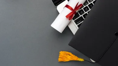 Rolled Diploma Tied with a Red Ribbon Rests on a Laptop Keyboard Beside a Graduation Cap with a Yellow Tassel El Verdadero Reto Del Tfg Y El Tfm Tiempo Presión Académica Y Desgaste Universitario Zaragozala Qué Hacer En Zaragoza
