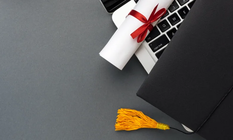 Rolled Diploma Tied with a Red Ribbon Rests on a Laptop Keyboard Beside a Graduation Cap with a Yellow Tassel El Verdadero Reto Del Tfg Y El Tfm Tiempo Presión Académica Y Desgaste Universitario Zaragozala Qué Hacer En Zaragoza