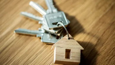 Key Ring with a Metal House shaped Wooden Tag on a Wood Surface in the Background Alquiler Asequible Zaragoza Así Optar a 78 Viviendas Zaragozala Qué Hacer En Zaragoza