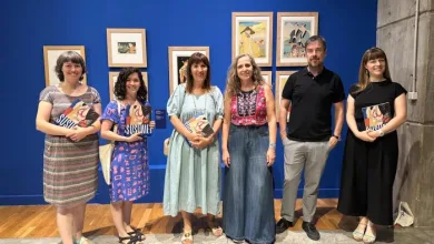 Six Adults Pose in an Art Gallery Against a Blue Wall Each Holding a Book with Framed Pictures Visible Behind Them on the Wall Exposición Japonesa En Zaragoza 77 Obras En El Iaacc Pablo Serrano Zaragozala   Qué Hacer En Zaragoza