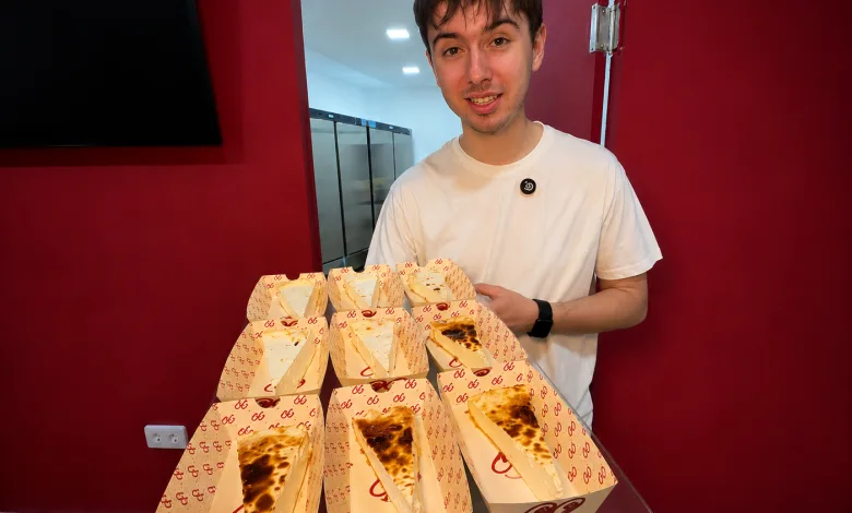 Young Man in a White T shirt Stands Behind a Table Displaying Multiple Opened Pizza Boxes Arranged Like Wedges on a Counter in a Red walled Room 99cheesecake Llega a Calle Alfonso En Pleno Auge De Las Tartas De Queso Zaragozala Qué Hacer En Zaragoza