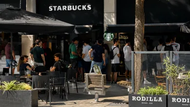 Crowd Lines Up Outside a Starbucks Cafe with Outdoor Seating Under Large Umbrellas and a Rodilla Sign Nearby on the Sidewalk El Ajedrez Efecto Llamada En El Coso De Zaragoza Para Desafiar a Los hombres De Rojo Zaragozala   Qué Hacer En Zaragoza