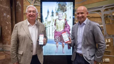 Two Men in Business Attire Pose Beside a Large Touchscreen Display Featuring a Statue Each Man Holds a Smartphone Zaragozapp Lanza Zésar Para Facilitar Trámites Municipales Zaragozala   Qué Hacer En Zaragoza