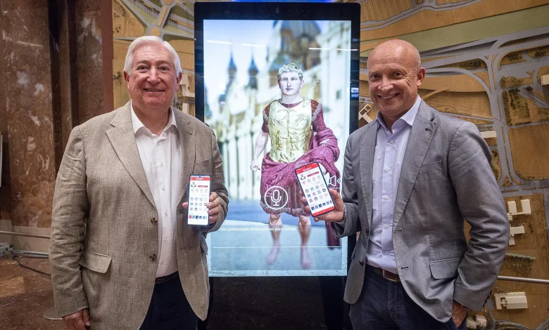 Two Men in Business Attire Pose Beside a Large Touchscreen Display Featuring a Statue Each Man Holds a Smartphone Zaragozapp Lanza Zésar Para Facilitar Trámites Municipales Zaragozala   Qué Hacer En Zaragoza