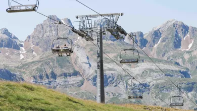 Chairlift Carrying Three Riders over a Green Hillside with Rugged Alpine Mountains in the Background Astún Abre El Verano Con El Telesilla Los Lagos Zaragozala   Qué Hacer En Zaragoza
