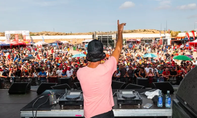 Dj on Stage with Pink Shirt Raises Right Arm to Cheering Crowd at a Large Outdoor Festival Mixing Gear in Front of Him Zaragozala | Agenda Cultural Ocio Y Planes En Zaragoza Página 1413 Zaragozala Qué Hacer En Zaragoza