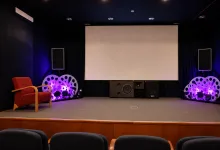 Stage Setup in a Small Theater Large Blank Screen Center Purple lit Speakers and Decorative Circular Props on Both Sides and a Red Armchair on the Left Zaragozala | Agenda Cultural Ocio Y Planes En Zaragoza   Página 1411 Zaragozala   Qué Hacer En Zaragoza