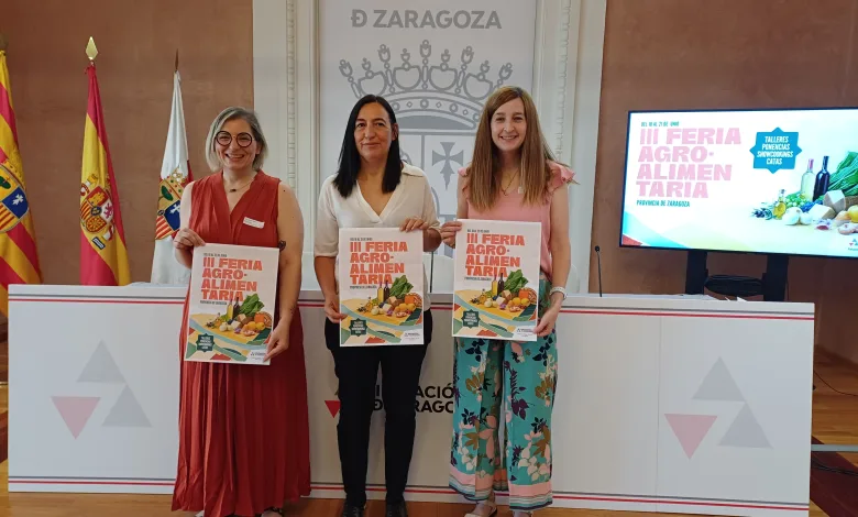 Three Women Stand Side by Side Each Holding a Brochure for a Regional Fair in a Formal Presentation Room with Flags and a Screen to the Right Zaragozala | Agenda Cultural Ocio Y Planes En Zaragoza Página 189 Zaragozala Qué Hacer En Zaragoza
