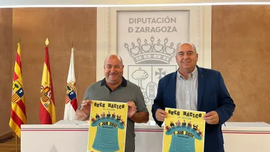 Two Men in a Formal Setting Hold Bright Posters in Front of the Zaragoza Provincial Council Emblem and Flags in the Background Festival Orés Mágico 2026 Información Y Actividades Zaragozala   Qué Hacer En Zaragoza