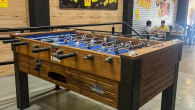 Indoor Foosball Table with a Wooden Finish and Black Legs Players Are on the Rods in a Space with Yellow Posters on the Wall at the Back Zaragozala | Agenda Cultural Ocio Y Planes En Zaragoza Zaragozala   Qué Hacer En Zaragoza