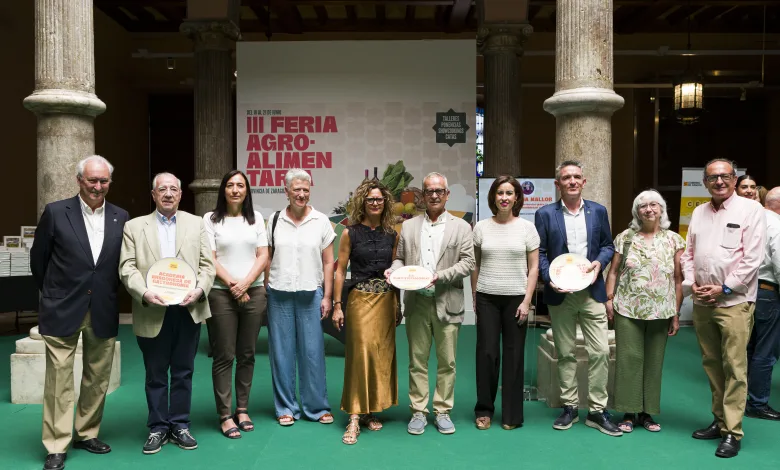 Group of People Posing for a Photo at an Agro food Fair Holding Plates in Front of a Banner Reading iii Feria Agro alimentaria in a Hall with Stone Columns and a Green Carpet Zaragozala | Agenda Cultural Ocio Y Planes En Zaragoza Zaragozala Qué Hacer En Zaragoza