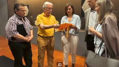 Five Adults Stand in an Exhibition Space As a Man in a Yellow Shirt Hands Orange Patterned Papers to a Woman in a Striped Blouse While Others Look On Zaragozala | Agenda Cultural Ocio Y Planes En Zaragoza Zaragozala   Qué Hacer En Zaragoza