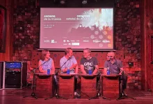 Panel Discussion with Four People Seated at Wooden Desks on Stage Microphones in Front of Them Awaiting Questions a Projection Screen Behind Shows Event Graphics Zaragozala | Agenda Cultural Ocio Y Planes En Zaragoza Zaragozala Qué Hacer En Zaragoza