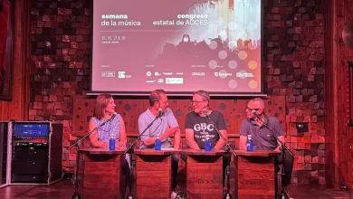 Panel Discussion with Four People Seated at Wooden Desks on Stage Microphones in Front of Them Awaiting Questions a Projection Screen Behind Shows Event Graphics Zaragozala | Agenda Cultural Ocio Y Planes En Zaragoza Zaragozala   Qué Hacer En Zaragoza
