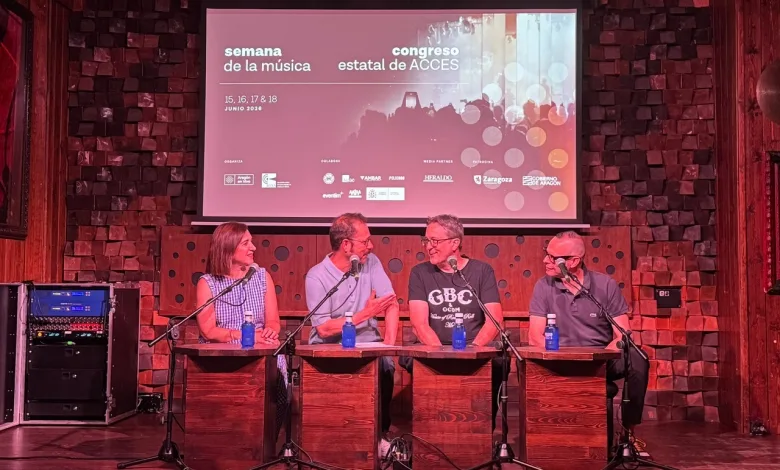 Panel Discussion with Four People Seated at Wooden Desks on Stage Microphones in Front of Them Awaiting Questions a Projection Screen Behind Shows Event Graphics Zaragozala | Agenda Cultural Ocio Y Planes En Zaragoza Zaragozala Qué Hacer En Zaragoza