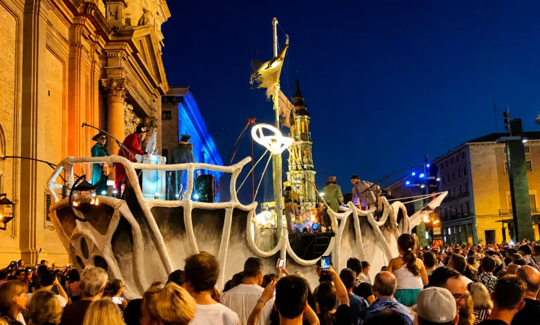 Nighttime Parade Float Shaped Like White Bones Atop a Large Cart Crowd Filming and Watching in a Lit Urban Square La Noche En Blanco Reúne a Casi 38000 Personas En Zaragoza Zaragozala   Qué Hacer En Zaragoza