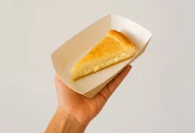 Hand Holding a White Takeout Box with a Slice of Cheesecake Inside the Box Las Tartas De Queso Más Baratas De España Llegan Al Centro De Zaragoza Zaragozala   Qué Hacer En Zaragoza