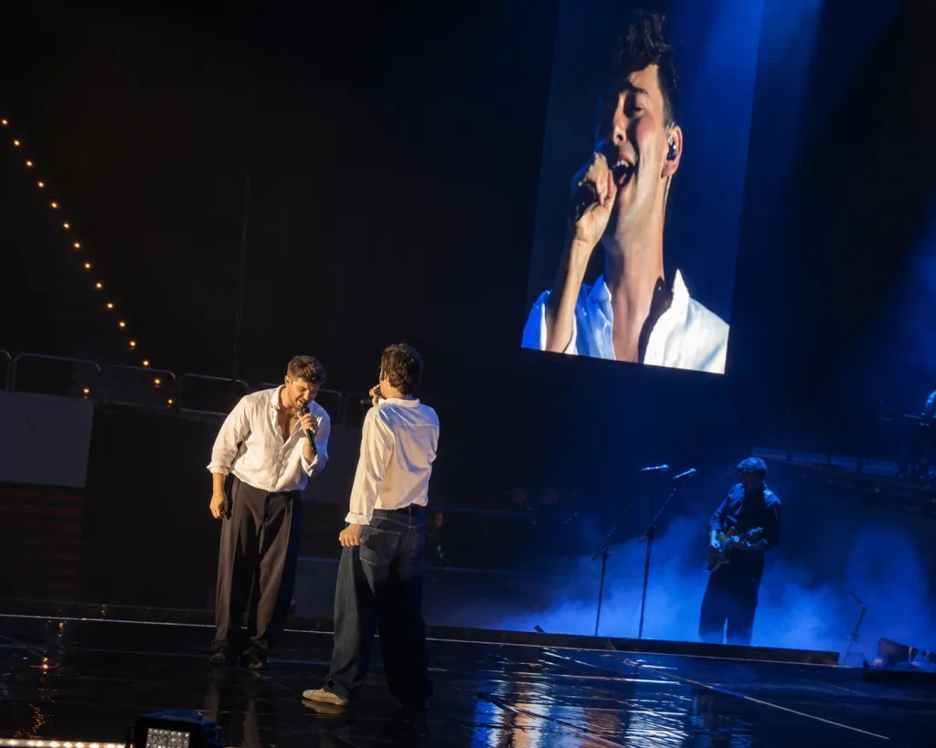 Two Male Singers in White Shirts Perform on a Dark Stage a Large Screen Shows a Close up of the Lead Singer Pablo Alborán Encandila a Cerca De 6000 Personas En Zaragoza Zaragozala   Qué Hacer En Zaragoza
