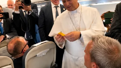 Pope Francis in White Robes on a Plane Hands a Small Yellow Item to a Seated Passenger While Photographers and Staff Observe Nearby El Papa León Xiv Recibe Una Cinta Del Pilar En Su Viaje a Espala Zaragozala   Qué Hacer En Zaragoza