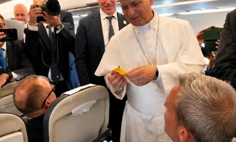 Pope Francis in White Robes on a Plane Hands a Small Yellow Item to a Seated Passenger While Photographers and Staff Observe Nearby El Papa León Xiv Recibe Una Cinta Del Pilar En Su Viaje a Espala Zaragozala Qué Hacer En Zaragoza