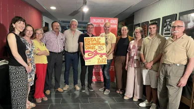 Group of Adults Posing for a Photo Indoors Around a Festival Poster and Red Banner That Reads Longaniza De Graus All Smiling at the Camera La Fiesta De La Longaniza De Graus 2026 Ya Tiene Cartel Zaragozala Qué Hacer En Zaragoza