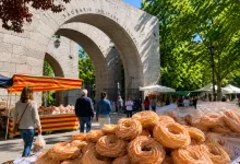 Market Stalls Under a Stone Arch Labeled Sacrario Militare Italiano Foreground Shows a Pile of Sugar dusted Pastries on a Table La Tradición Que Cada 13 De Junio Llena De Rosquillas La Iglesia De San Antonio Zaragozala   Qué Hacer En Zaragoza
