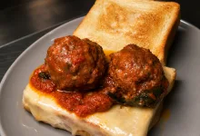 Two Meatballs in Tomato Sauce Resting on Melted Cheese Atop a Slice of Toasted Bread with a Second Toasted Slice on the Plate Los Auténticos Sándwiches De Nueva York Aterrizan En Zaragoza Zaragozala   Qué Hacer En Zaragoza