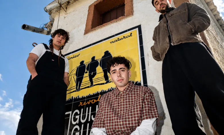 Three Young Men Pose in Front of a Bright Yellow Mural on a Weathered White Building Under a Blue Sky Conciertos Agotados En Pirineos Sur 2026 Y últimas Entradas Zaragozala Qué Hacer En Zaragoza