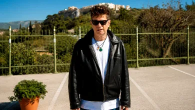 Man in a Black Leather Jacket and White Shirt Stands in a Parking Lot with a Green Fence and Hillside Behind Him Santiago Auserón Premio De Las Letras Aragonesas 2025 Zaragozala Qué Hacer En Zaragoza