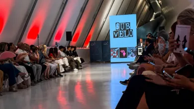 Audience Seated Along a Glossy Runway in a Futuristic Venue with Red Wall Wash a Large Blue Screen Reading sub Velo Near a Speaker Stage Cinco Diseñadores Aragoneses Debutan En Sub Velo Zaragozala Qué Hacer En Zaragoza