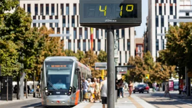 Digital Timetable Display on a Tram Stop Pole with a Silver Tram Arriving and Pedestrians on the Platform in a City Square Ola De Calor En Zaragoza Máximas De Hasta 43 Grados Zaragozala   Qué Hacer En Zaragoza