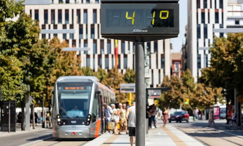 Digital Timetable Display on a Tram Stop Pole with a Silver Tram Arriving and Pedestrians on the Platform in a City Square Ola De Calor En Zaragoza Máximas De Hasta 43 Grados Zaragozala Qué Hacer En Zaragoza